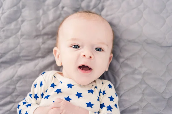 Blick von oben auf ein entzückendes kleines Baby, das auf einer grauen Decke liegt — Stockfoto