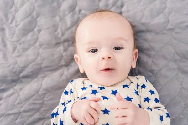 Blick von oben auf ein entzückendes kleines Baby, das auf einer grauen Decke liegt — Stockfoto