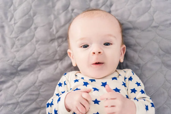 Overhead view of adorable little baby lying on grey blanket — Stock Photo