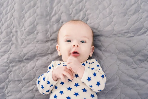 Overhead view of adorable little baby lying on grey blanket — Stock Photo