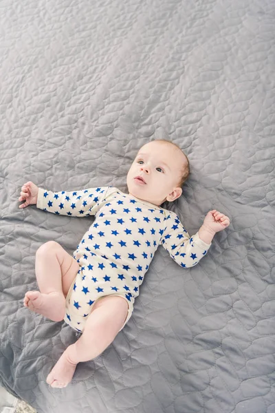 Close up view of adorable little baby lying on grey blanket — Stock Photo