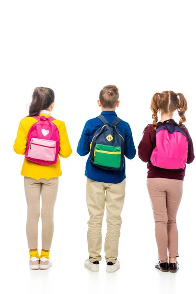 Vista posterior de los escolares con mochilas multicolores aisladas en blanco - foto de stock