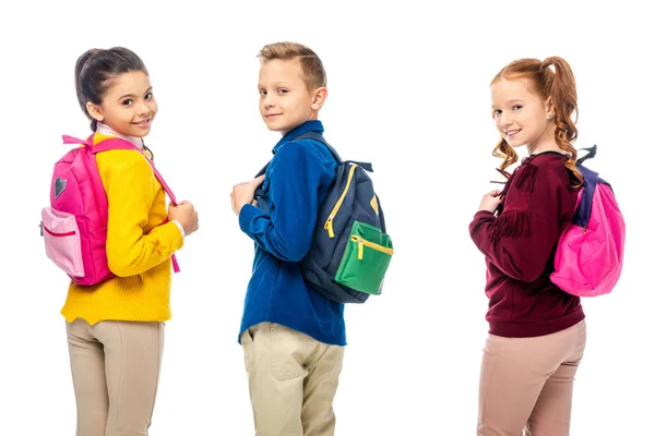 Schoolchildren with multicolored backpacks smiling at camera isolated on white — Stock Photo