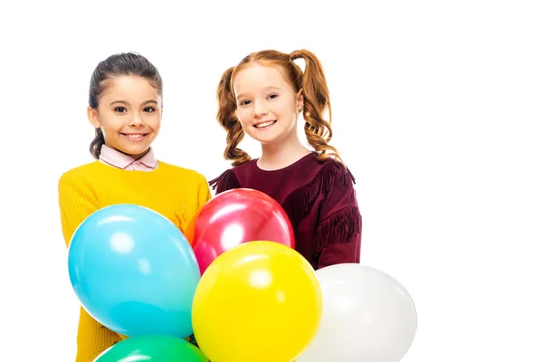 Niedliche Schulmädchen lächeln, halten bunte Luftballons in der Hand und schauen vereinzelt in die Kamera auf weiß — Stockfoto