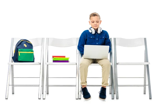 Bonito estudante sentado na cadeira e usando laptop isolado no branco — Fotografia de Stock