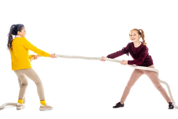 Two cheerful schoolgirls pulling rope isolated on white — Stock Photo