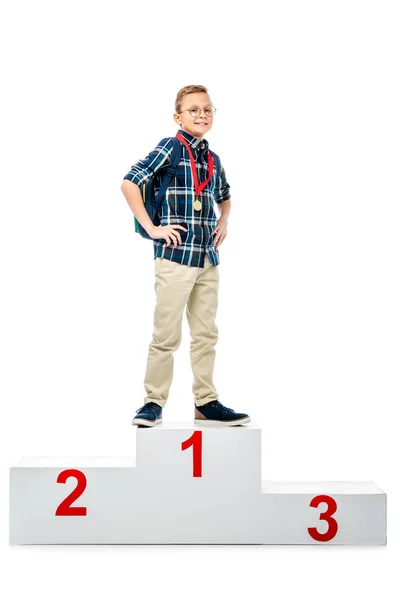 Happy boy standing on winner podium, smiling and looking at camera isolated on white — Stock Photo