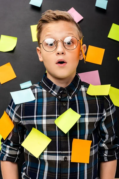 Surprised boy with multicolored stickers looking at camera on black background — Stock Photo