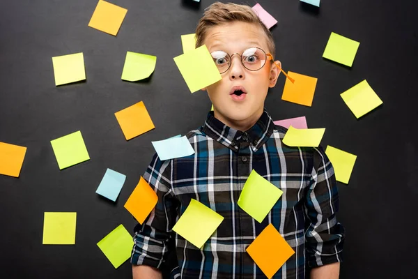 Surprised boy in glasses with multicolored stickers looking at camera on black background — Stock Photo