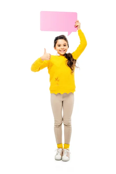 Весела школярка тримає рожеву бульбашку мови над головою, показуючи великий палець вгору і дивлячись на камеру ізольовано на білому — стокове фото