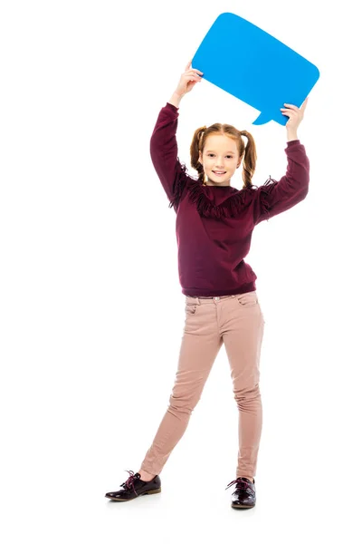 Улыбающаяся школьница, держащая синий пузырь речи над головой и смотрящая на камеру, изолированную на белом — стоковое фото