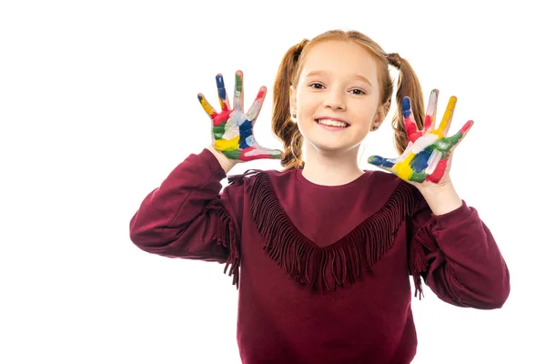 Écolière souriante regardant la caméra et montrant les mains peintes dans des peintures colorées isolées sur blanc — Photo de stock