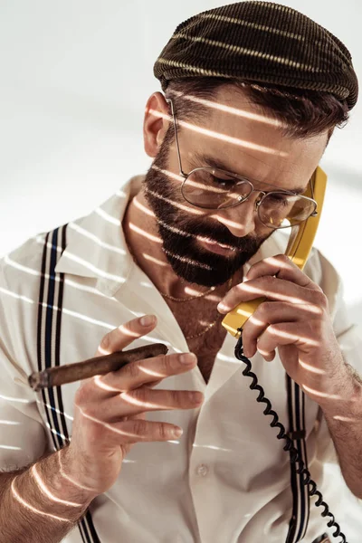 Handsome bearded man talking on phone and holding cigar — Stock Photo