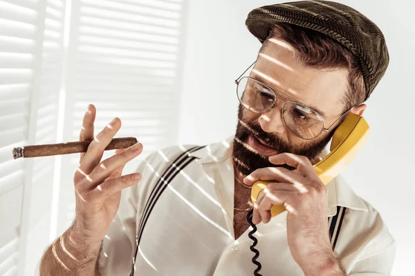 Hombre guapo en gafas hablando por teléfono y sosteniendo cigarro - foto de stock