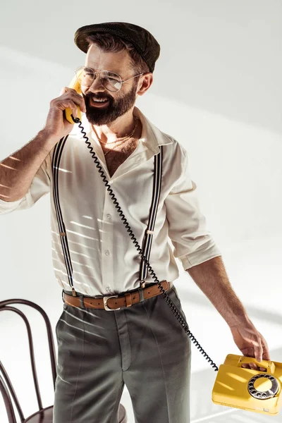 Bonito barbudo homem sorrindo e falando no retro telefone — Fotografia de Stock