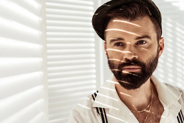 Handsome bearded man in cap near white room divider — Stock Photo