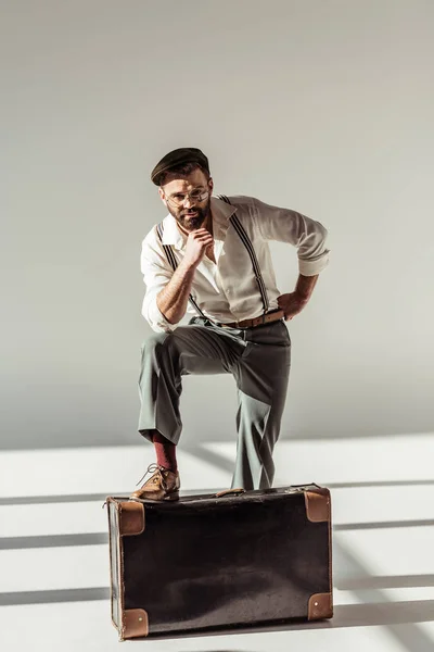 Handsome bearded man near retro suitcase and looking at camera on grey background — Stock Photo