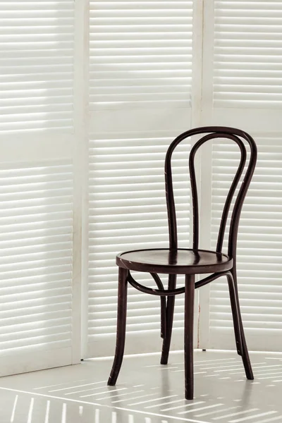 Black wooden chair and white room divider with shadows — Stock Photo