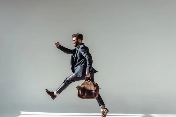 Homem barbudo com saco marrom pulando sobre fundo cinza — Fotografia de Stock