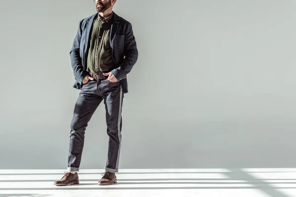 Cropped view of man with hands in pockets standing on grey background — Stock Photo