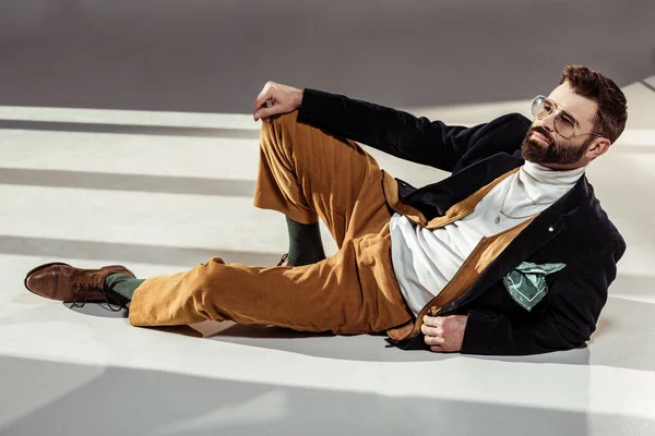 Handsome stylish bearded man in glasses lying on floor — Stock Photo