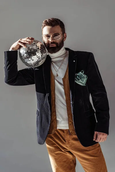 Bearded man holding disco ball on shoulder and looking at camera isolated on grey — Stock Photo