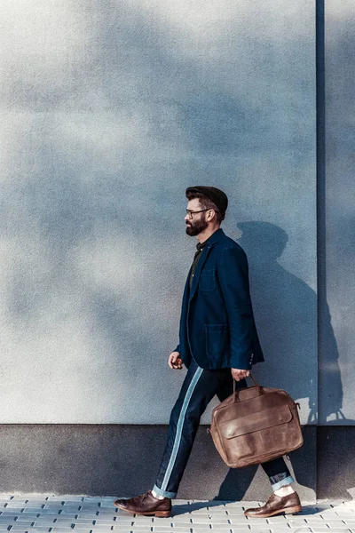 Handsome bearded man in glasses walking and holding bag — Stock Photo