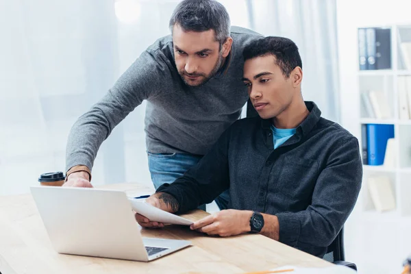 Two focused businessmen working with papers and laptop in office — Stock Photo