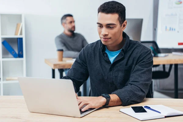 Schöner junger Geschäftsmann arbeitet mit Laptop im Büro — Stockfoto