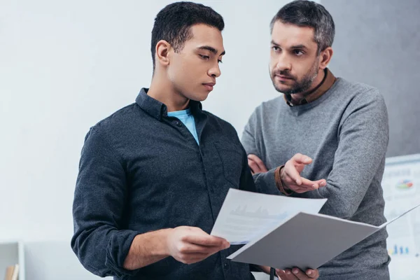 Empresarios sosteniendo carpeta con papeles y discutiendo el proyecto en la oficina - foto de stock