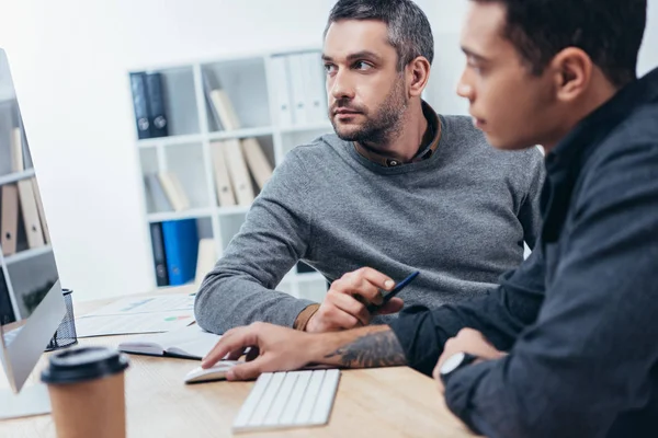 Compañeros de trabajo profesionales serios que utilizan la computadora de escritorio y trabajan juntos en la oficina - foto de stock