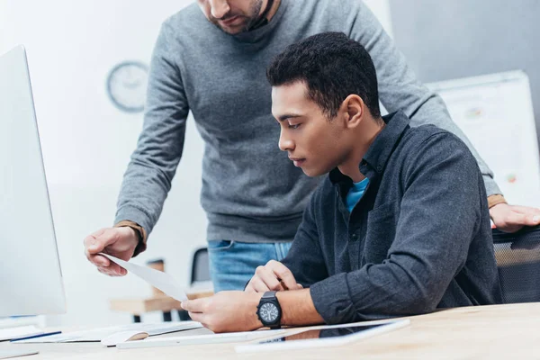 Cropped shot of two businessmen looking at document at workplace — Stock Photo