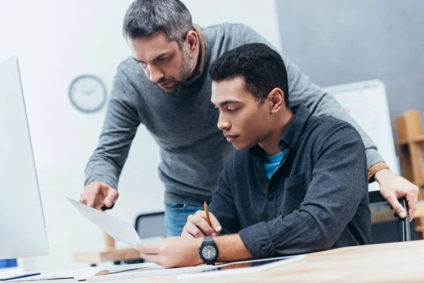 Colegas de negocios concentrados discutiendo documentos en el lugar de trabajo - foto de stock