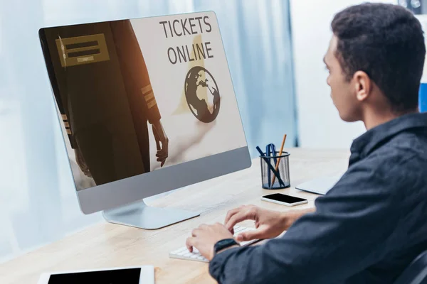 Joven hombre de negocios utilizando el ordenador de sobremesa con entradas sitio web en línea en la pantalla en la oficina - foto de stock