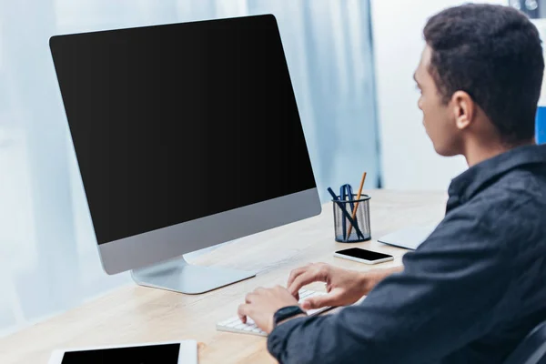 Jeune homme d'affaires utilisant un ordinateur de bureau avec écran blanc dans le bureau — Photo de stock