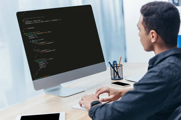 Молодий бізнесмен, використовуючи настільного комп'ютера з html-код на екрані в офісі — стокове фото