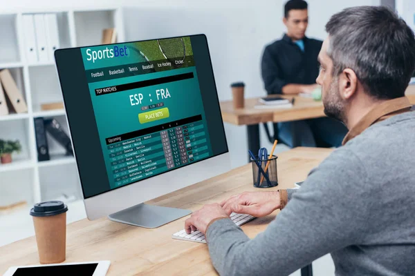 Uomo d'affari che utilizza il computer desktop con il sito di scommesse sportive sullo schermo in ufficio — Foto stock