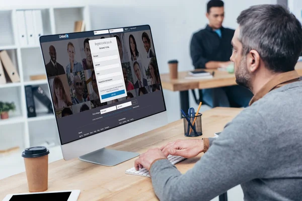Бизнесмен использует настольный компьютер с веб-сайтом linkedin на экране в офисе — стоковое фото