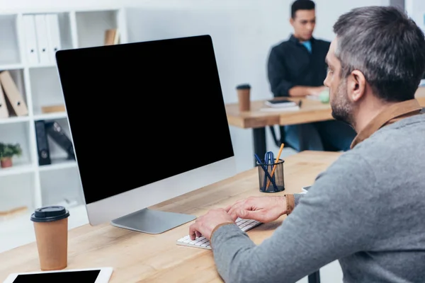 Empresário usando computador desktop com tela em branco no escritório — Fotografia de Stock