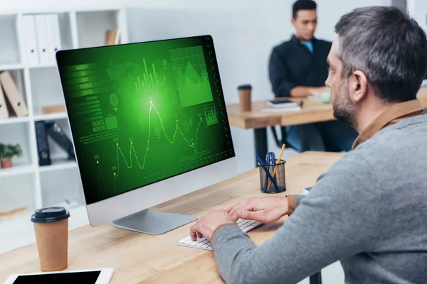 Uomo d'affari che utilizza il computer desktop con grafici e grafici sullo schermo in ufficio — Foto stock