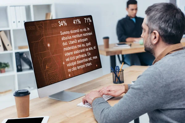 Бізнесмен використовує настільний комп'ютер зі статистикою на екрані в офісі — стокове фото