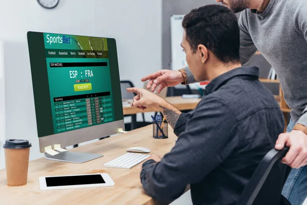 Обрізаний знімок бізнес-колег, використовуючи настільний комп'ютер зі спортивним веб-сайтом на екрані в офісі — стокове фото
