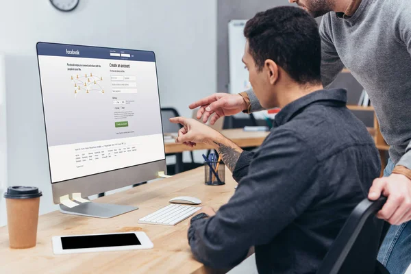 Plan recadré de collègues d'affaires en utilisant un ordinateur de bureau avec facebook site Web à l'écran dans le bureau — Photo de stock