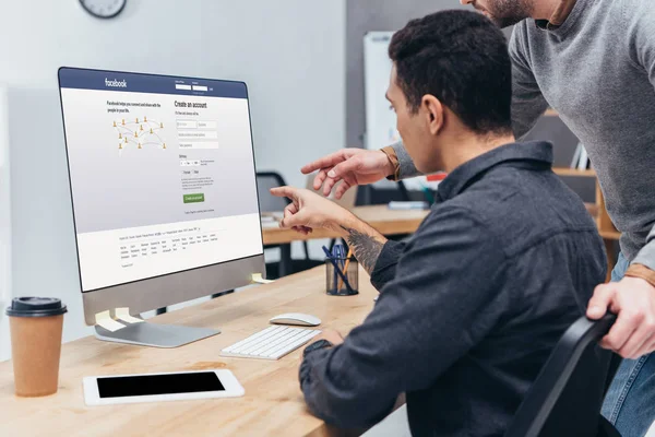 Cropped shot of business colleagues using desktop computer with facebook website on screen in office — Stock Photo