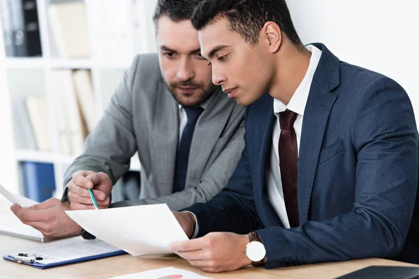 Due uomini d'affari concentrati che lavorano con documenti in carica — Foto stock