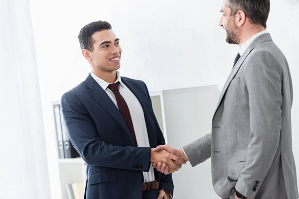 Hombre de negocios profesional estrechando las manos y sonriendo entre sí en la oficina - foto de stock