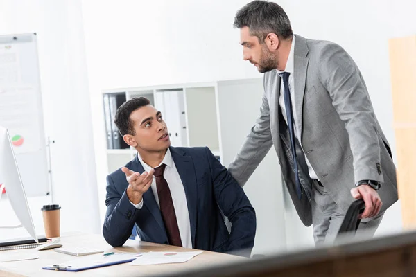 Серйозні професійні бізнесмени розмовляють і дивляться один на одного в офісі — стокове фото