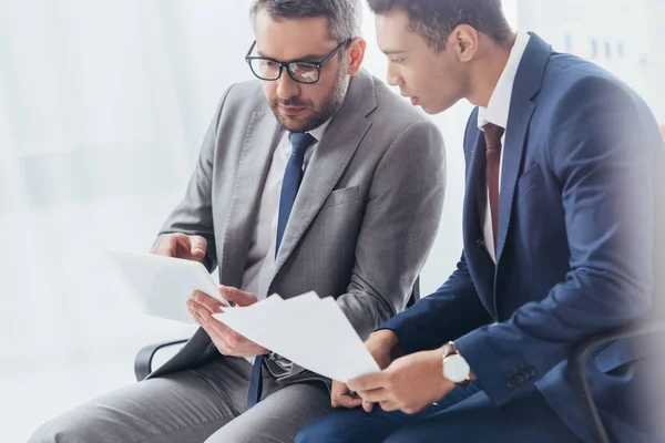 Uomini d'affari concentrati che lavorano con documenti e tablet digitali in ufficio — Foto stock