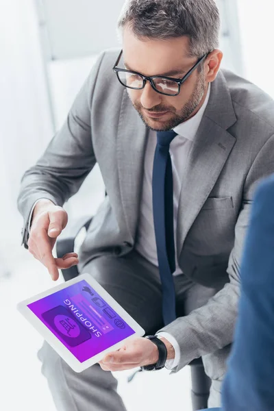 Vista de ángulo alto de hombre de negocios guapo en gafas usando tableta digital con aplicación de compras - foto de stock