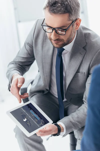 Vue grand angle de bel homme d'affaires dans les lunettes à l'aide d'une tablette numérique avec application tumblr à l'écran — Photo de stock